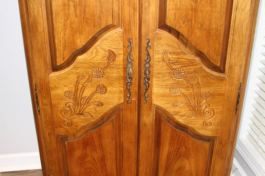 Closeup of floral carvings and metal handles on armoire doors