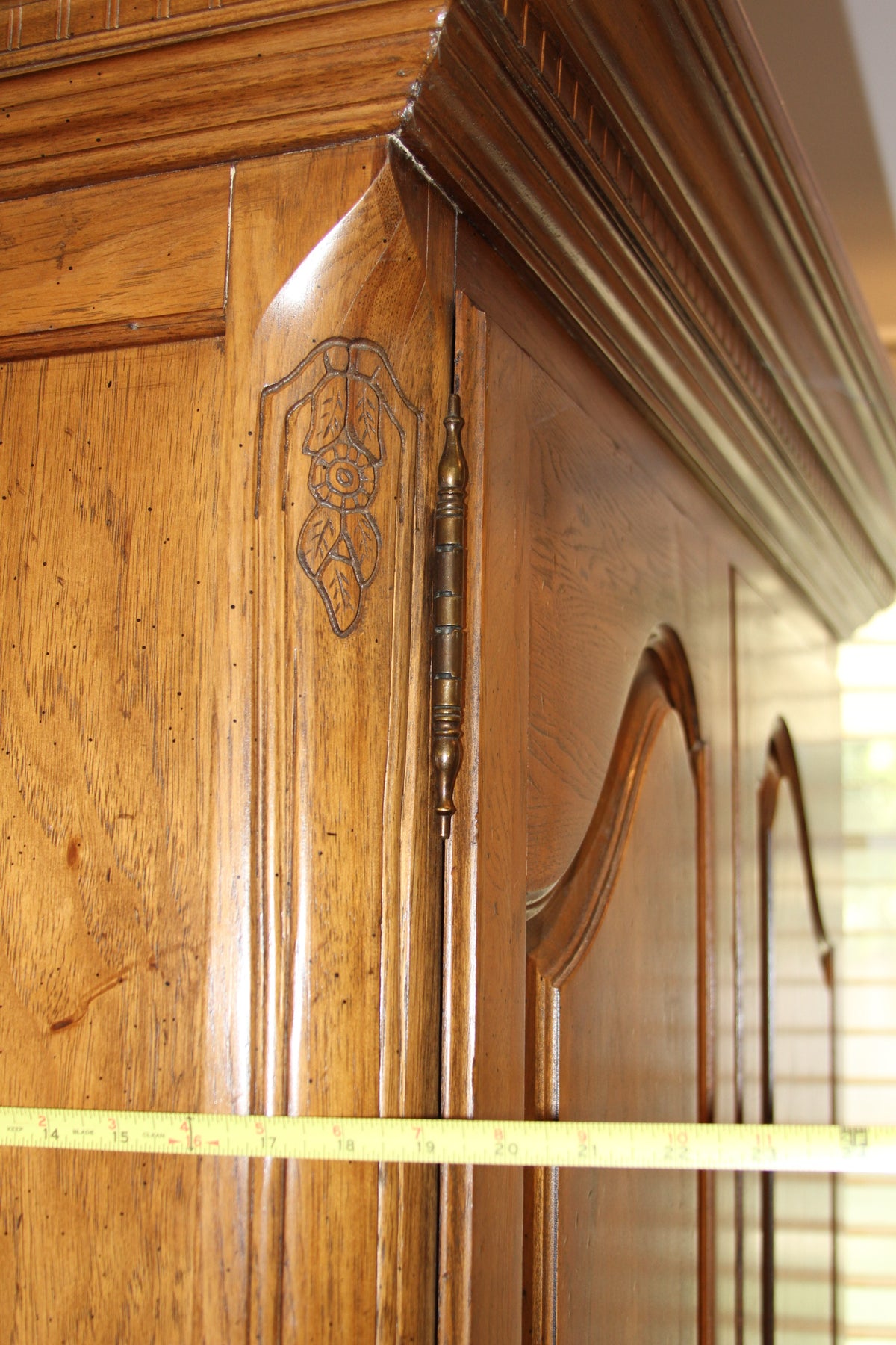 Side view of armoire with decorative floral carving and hinge