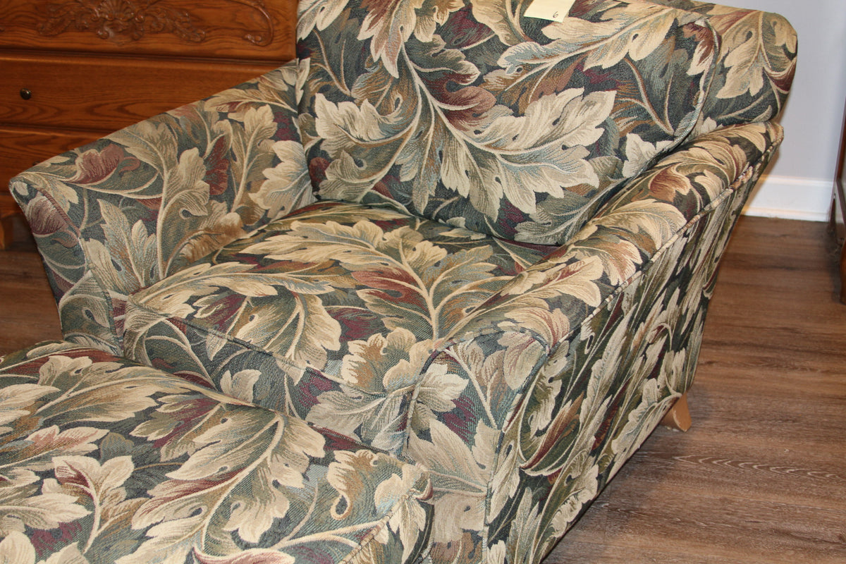 Angled view of club chair with rolled arms and leaf design upholstery