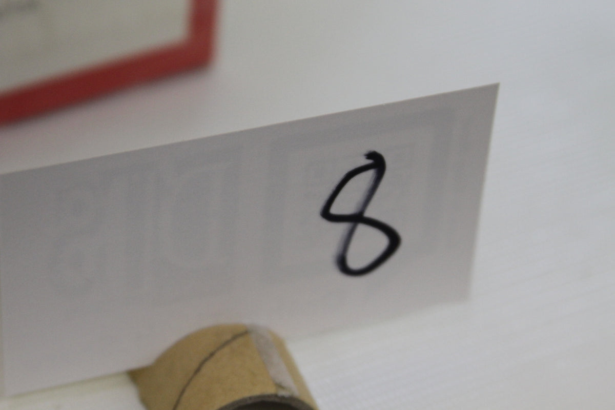 White card with the number 8 displayed near cardboard tube