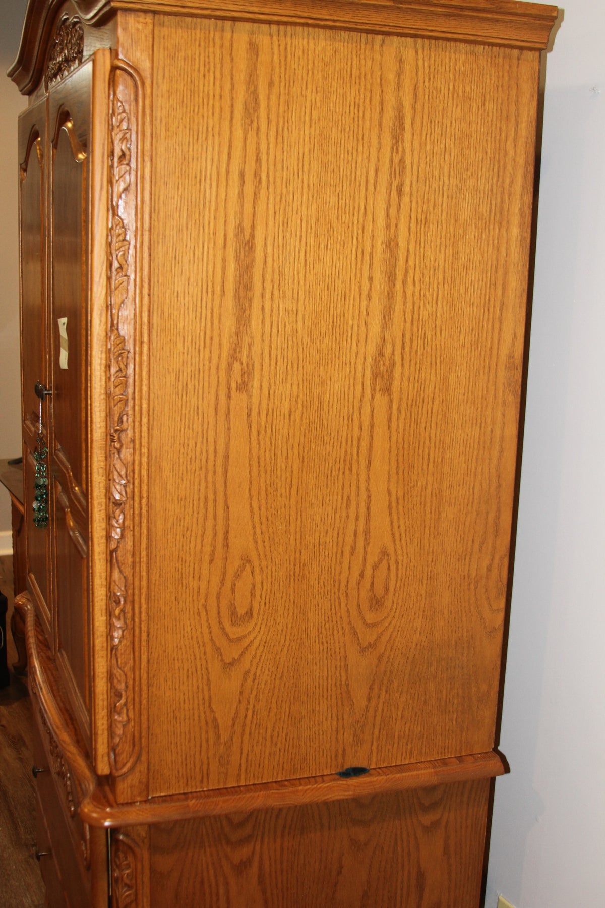 Side view of oak armoire showing wood grain and carved trim