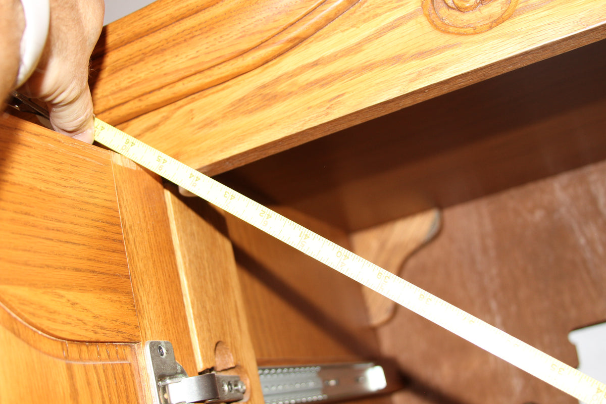 Measuring tape displaying interior width of armoire cabinet