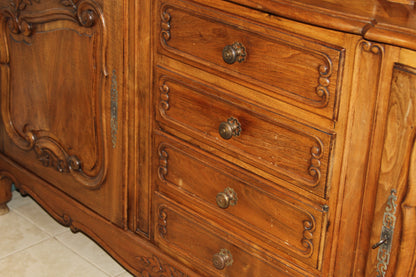 Detailed view of buffet drawers with ornate wooden carvings and antique knobs