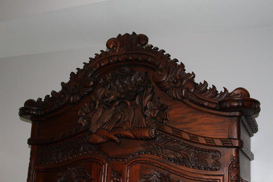 Close-up of ornate crest with floral carvings on armoire