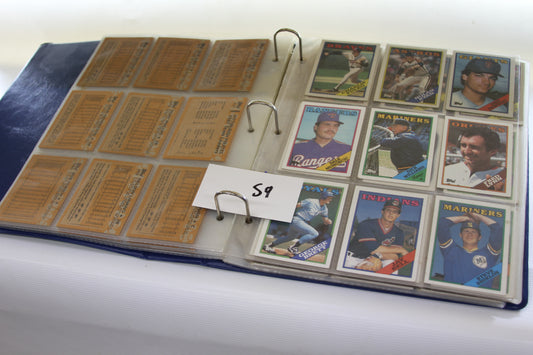 Open binder displaying 1988 Topps baseball cards and statistics