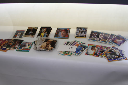 Assorted vintage baseball and basketball trading cards displayed on a white surface