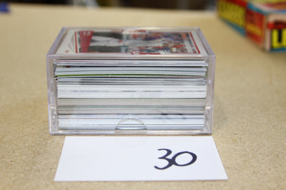 Baseball cards stacked in a clear storage case on a table