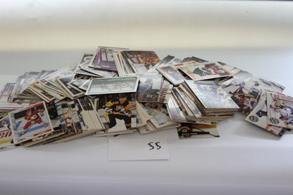 A scattered lot of NHL hockey trading cards on a white surface with a paper labeled '55'.