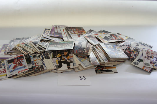 A scattered lot of NHL hockey trading cards on a white surface with a paper labeled '55'.