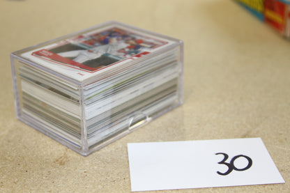 Angled view of baseball cards in clear plastic case next to a numbered card