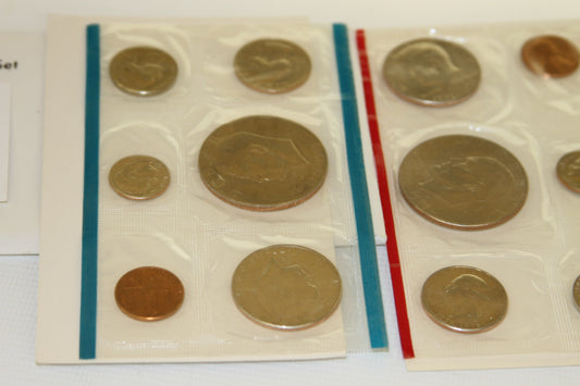 Close-up view of 1976 uncirculated coins in blue and red edged sleeves