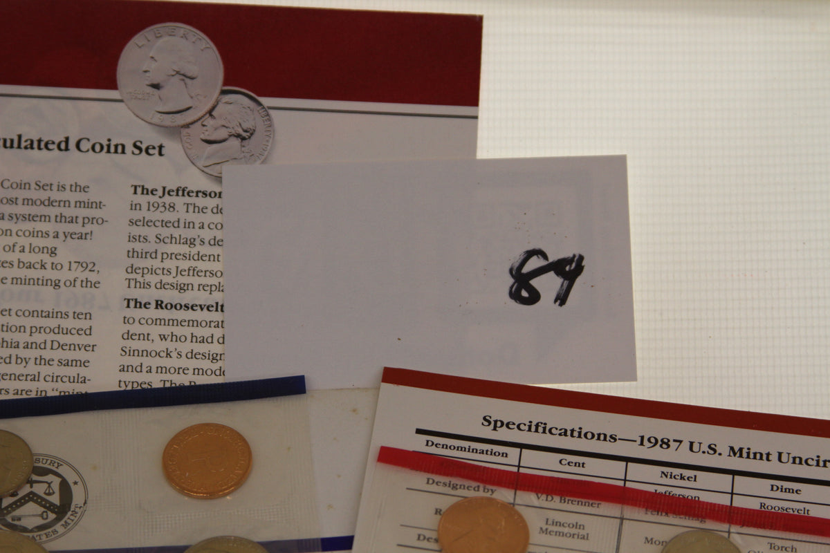 Close-up of coin set details, specification sheet, and handwritten number 84