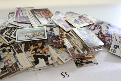 Another side view of the large pile of NHL hockey trading cards in assorted stacks.