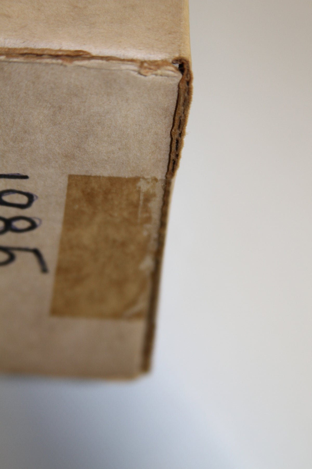 Detail of box's corner with handwritten label and tape