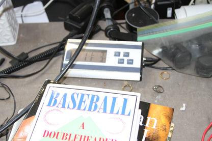 Baseball history books on a digital scale with cords and rings nearby