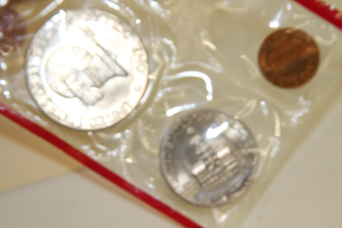 Back sides of 1976 Kennedy half dollar, quarter, and penny in red sleeve