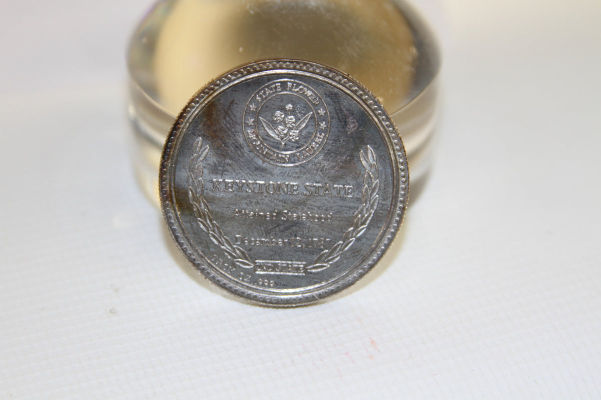 Back view of coin with state flower, laurel wreath, and Keystone State text