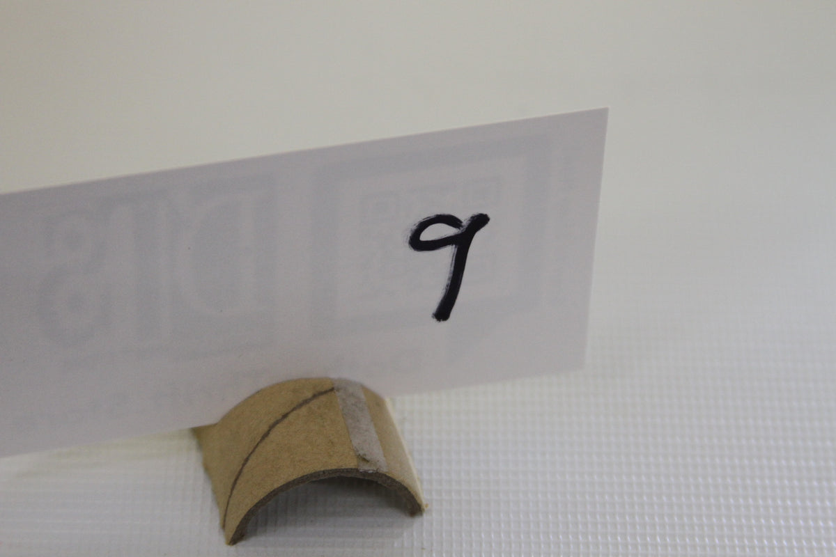 White card with handwritten number 9 in a cardboard holder