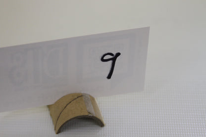 White card with handwritten number 9 in a cardboard holder