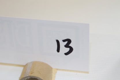 White card with handwritten number 13 in front of packaging