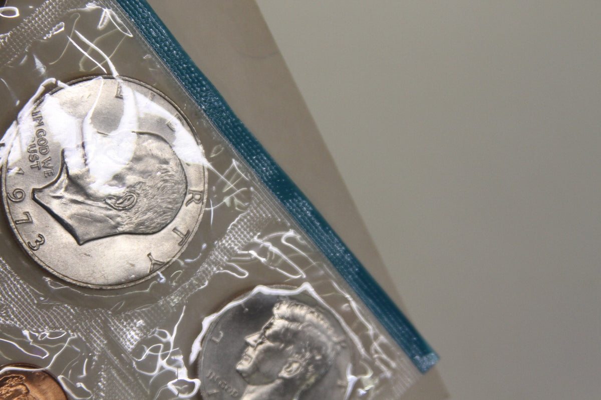 Close-up of Eisenhower dollar and Kennedy half dollar coins in blue-edged packaging