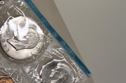 Close-up of Eisenhower dollar and Kennedy half dollar coins in blue-edged packaging