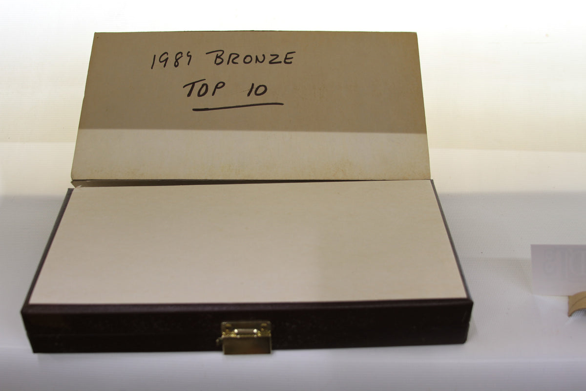 Open brown case labeled '1989 Bronze Top 10' with lid raised